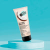 Tubo de exfoliante Coco Paradise Skin Super Good sobre un pedestal celeste
